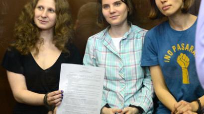 Ekaterina Samutsevich (C), Maria Alyokhina (L) and Nadezhda Tolokonnikova (R) show the court's verdict as they sit in a glass-walled cage in Moscow court on Agust 17, 2012 (AFP Photo / STR)