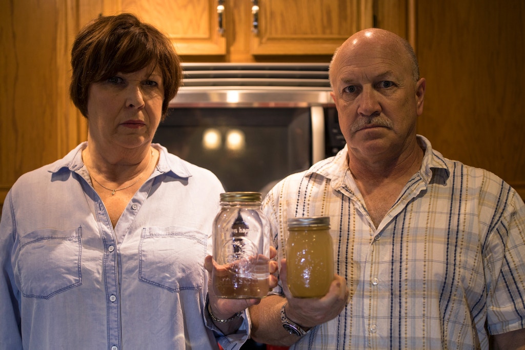 WEST WHITELAND, PENNSYLVANIA - OCTOBER 6: Homeowners Diane Salter, left, and David Mano, right, hold two jars with undrinkable clear and clouded well water caused by Sunoco's drilling for a natural gas liquids pipeline that contaminated their residential well October 6, 2017 in West Whiteland, Pennsylvania. Sunoco's horizontal drilling for their 350-mile Mariner East 2 pipeline project goes through Mano's and Slater's backyard and will eventually terminate in Sunoco's Marcus Hook Industrial Complex in on the Delaware coast for export. (Photo by Robert Nickelsberg/Getty Images)