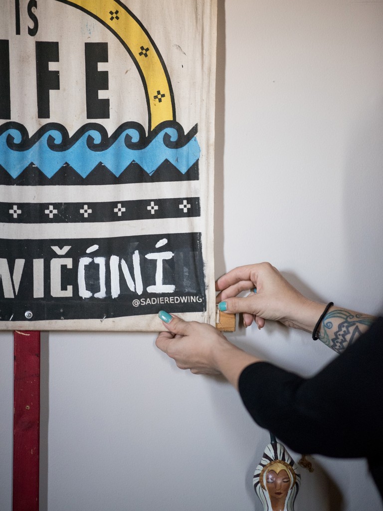 CAPTION: Jen Mendoza, an anti-pipeline activist who was affected by the surveillance actions of security contractor TigerSwan, adjusts a "Water if Life" banner that was at Standing Rock in her room at her home in Cincinnati, OH on Sunday, September 30, 2018. (Emma Joy Howells for The Intercept)
