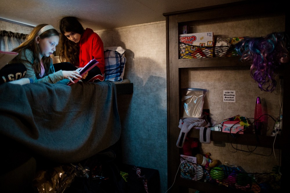 Michelle's Teixeira's 14 year old daughter (on the right) playing on her bed in their new trailer with a kid who also lost her home to the Camp Fire, Chico, California, December 21st, 2018. Michelle Teixeira is living in a 300 square foot trailer with her husband, her father, two daughters, and four dogs. Her husband’s boss owns a residential development made up of 36 empty lots, where the Teixeiras and five other families have made camp, calling themselves the “trailer treasures.” They’re all refugees from the Camp wildfire, which leveled Paradise, California, killing 86 people, including many retirees.Talia Herman for The Intercept