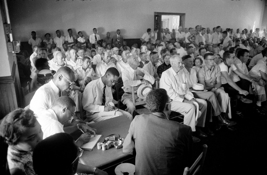 Interior view of the segregated seating in the packed Tallahatchie County Courthouse during the trial of J W Milam and Roy Bryant who were accused of the murder of Emmett Till, Sumner, Mississippi, September 1955. Till was a 14-year-old African-American boy from Chicago who had allegedly flirted with Bryant's wife, a white woman. Photojournalist Ernest Withers of the Chicago Defender is seated in center foreground with his back to the camera. (Photo by Ed Clark/The LIFE Picture Collection/Getty Images)  Ernest Withers (back to camera)