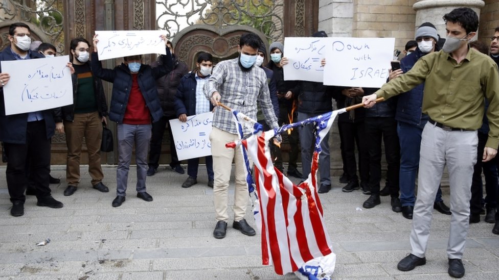 Students wearing facemasks and holding signs saying "Down with Israel" and others in Farsi burn Israeli and US flags in Tehran at a protest outside Iran's foreign ministry in Tehran (28 November 2020)