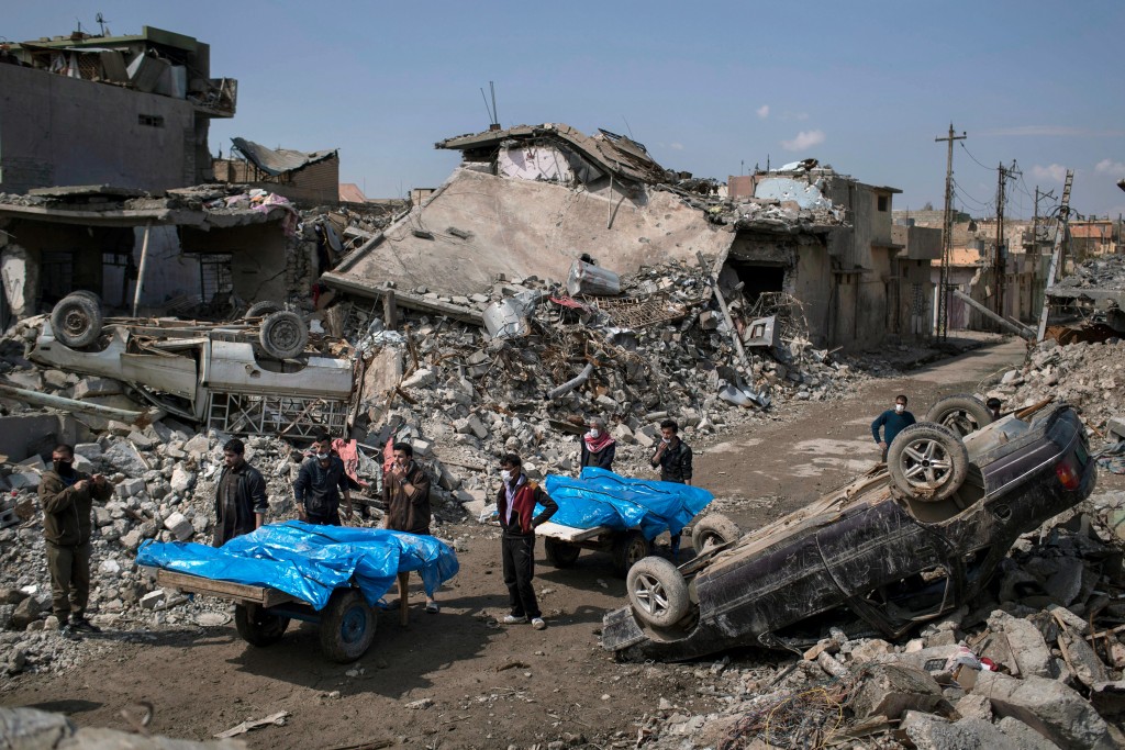 Residents carry the body of several people killed during fights between Iraq security forces and Islamic State on the western side of Mosul, Iraq, Friday, March 24, 2017. Residents of the Iraqi city's neighborhood known as Mosul Jidideh at the scene say that scores of residents are believed to have been killed by airstrikes that hit a cluster of homes in the area earlier this month (AP Photo/Felipe Dana)