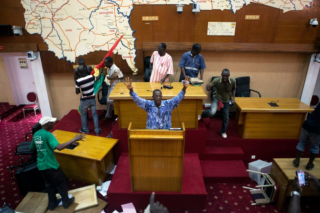 Anti-government protesters take over the parliament building in Ouagadougou, capital of Burkina Faso, October 30, 2014. Thousands of protesters marched on Burkina Faso's presidential palace after burning the parliament building and ransacking state television offices on Thursday, forcing President Blaise Compaore to scrap a plan to extend his 27-year rule. Emergency services said at least three protesters were shot dead and several others wounded by security forces when the crowd tried to storm the home of Compaore's brother. Security forces also fired live rounds and tear gas at protesters near the presidency in the Ouaga 2000 neighborhood. REUTERS/Joe Penney (BURKINA FASO - Tags: POLITICS CIVIL UNREST TPX IMAGES OF THE DAY) - RTR4C6YT